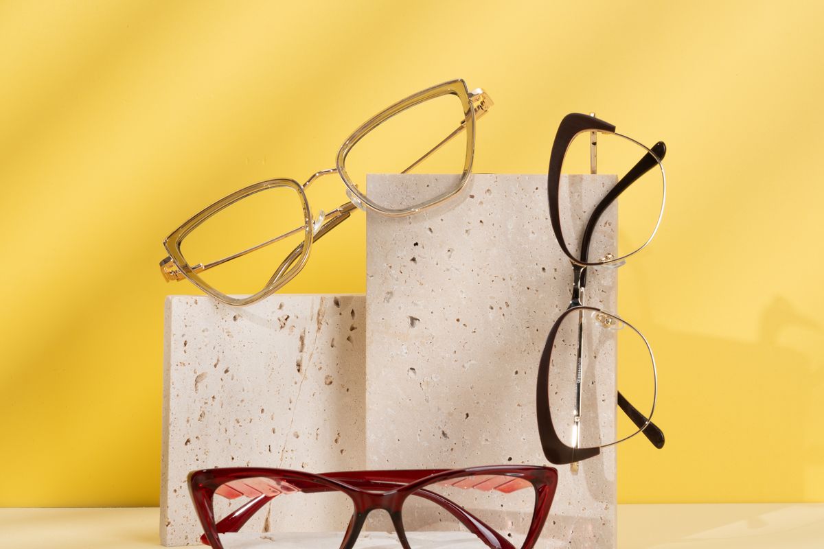 Two pairs of eyeglasses side by side on a wooden table