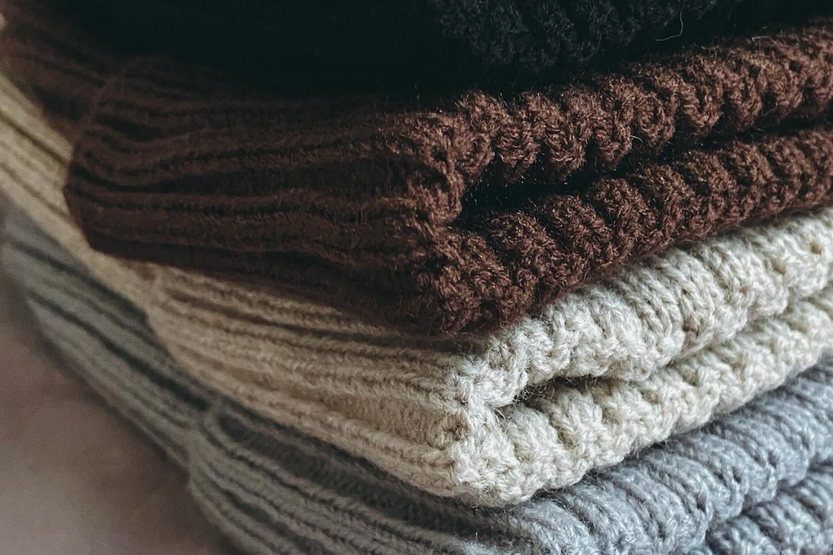 Folded ribbed-knit wool sweaters stacked in dark and neutral colors